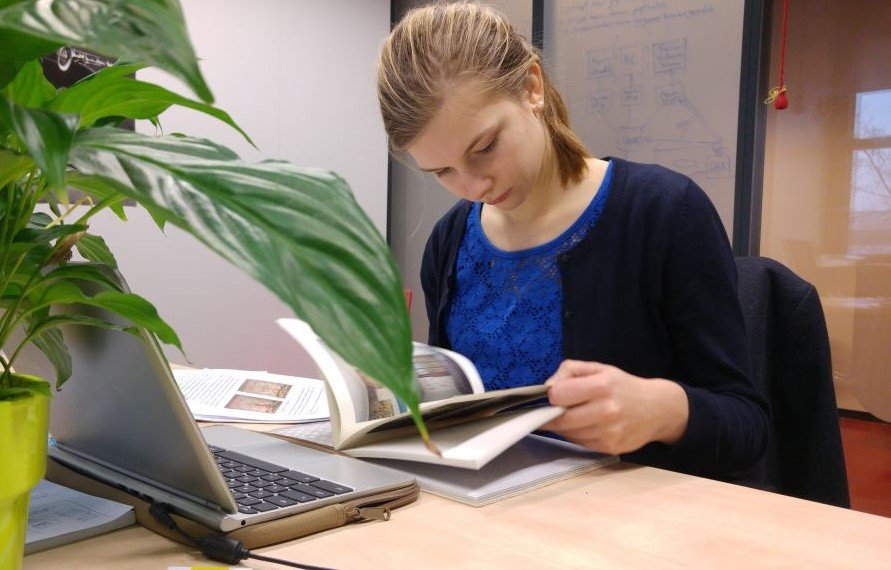 Studentessa concentrata nella lettura di un libro alla scrivania